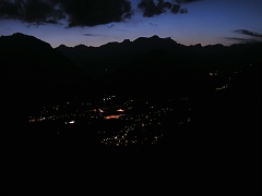 Arriva la sera : le luci della città e le sagome dei monti dal Rifugio